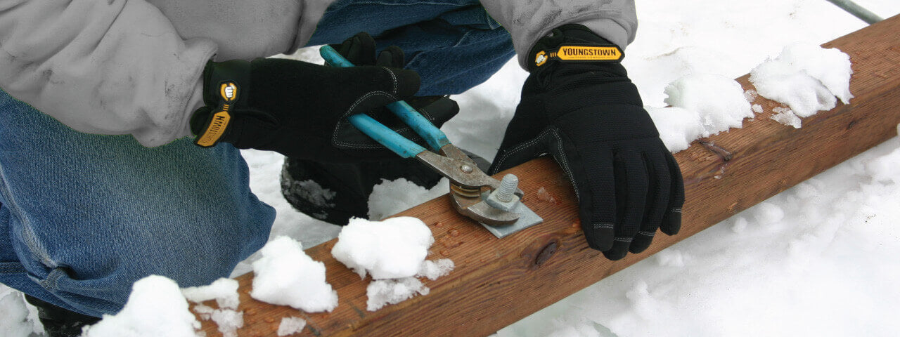 Man wearingYoungstown Waterprooof Winter Gloves with wrench in snow